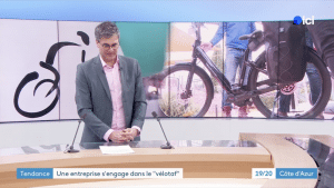 Présentateur TV avec écran vélo en fond, sujet sur le vélotaf, titres en bas Côte d'Azur.